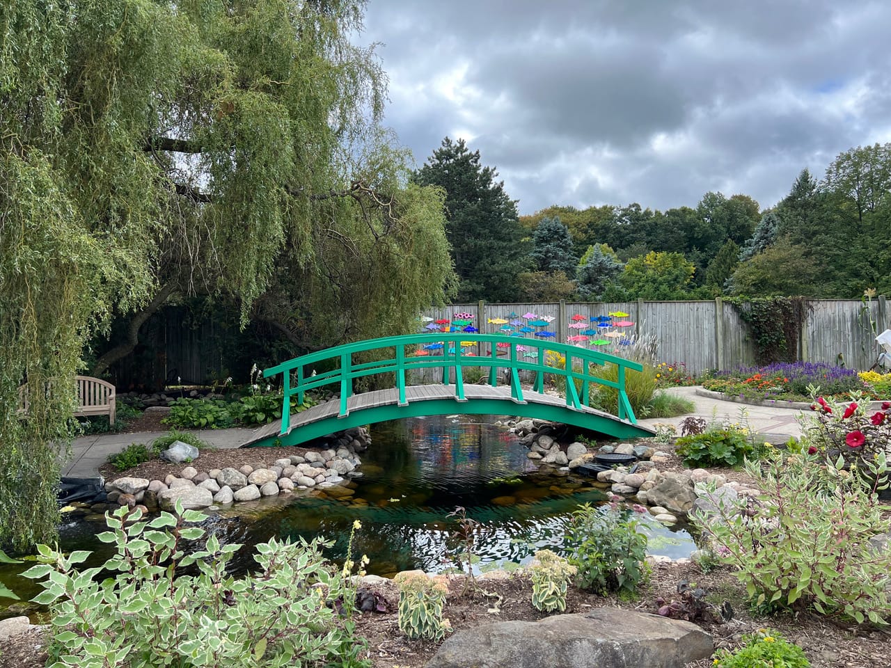 A green bridge over a pond in a garden.