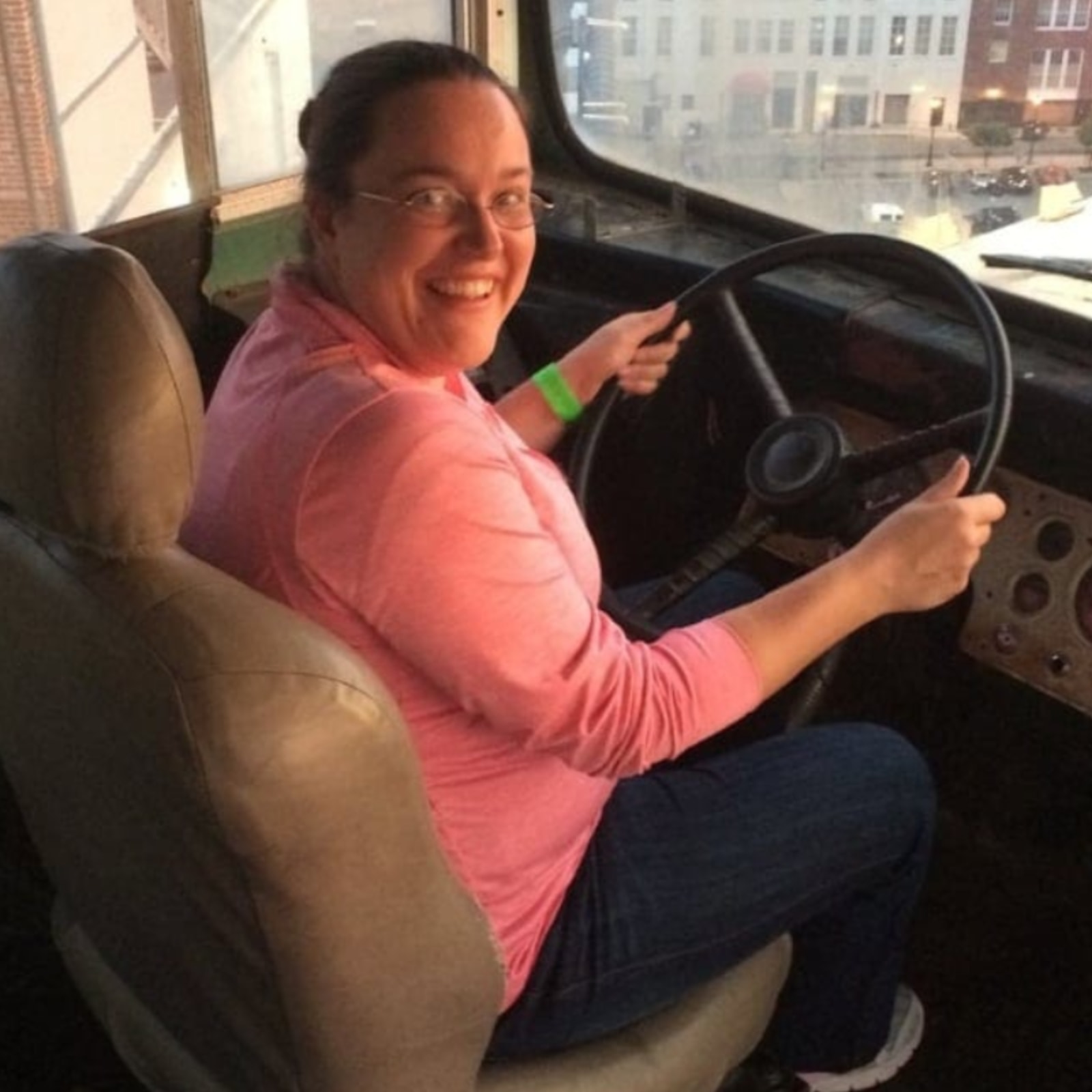 Sarah sitting in the driver's seat of a bus.