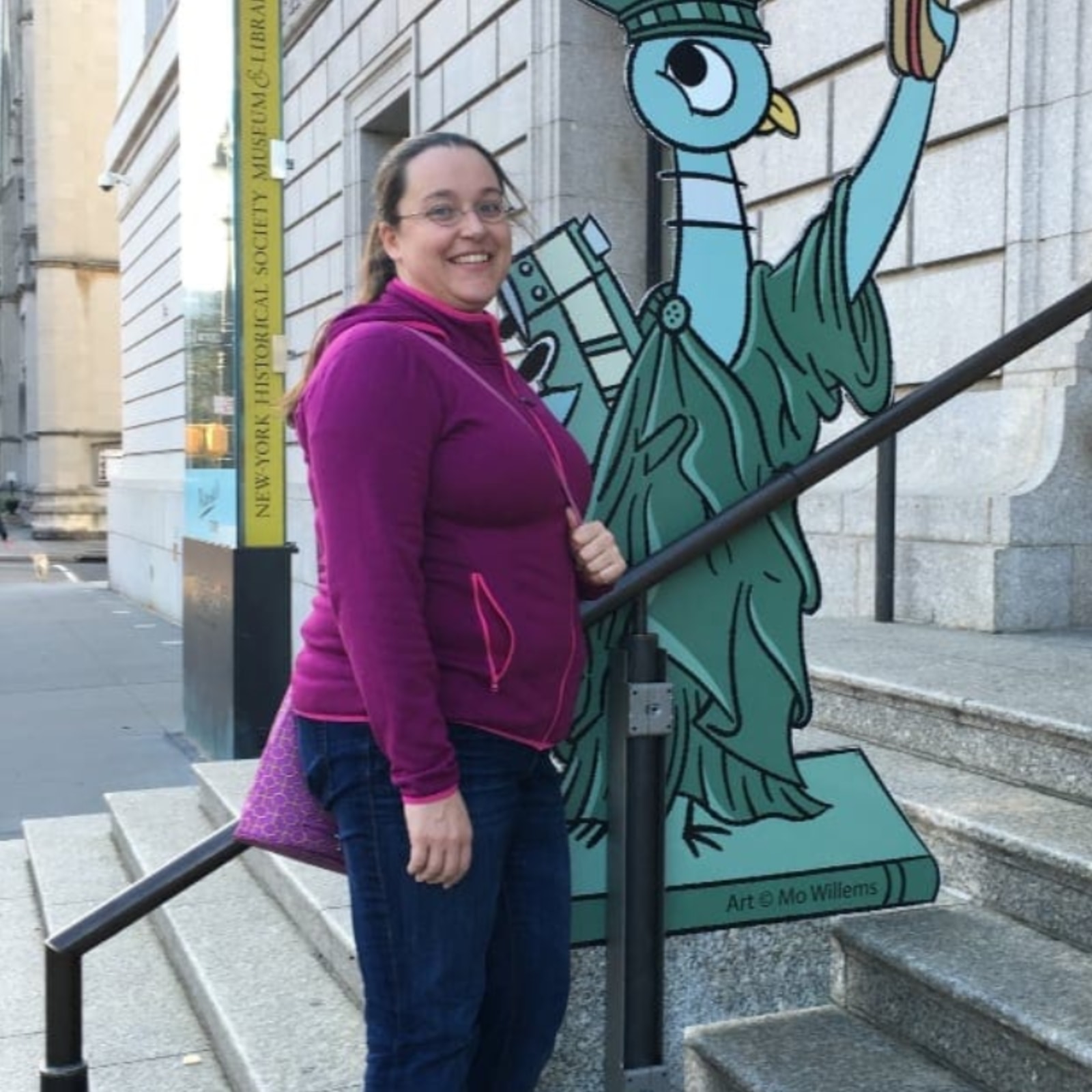 Sarah standing in front of a sketch by Mo Willems of the Statue of Liberty in NYC.